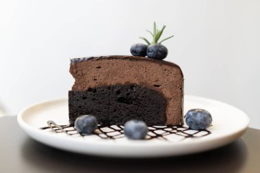 Çikolatalı kremalı pasta. Çikolatalı kek tabanı, kremalı krema dolgusu ve üzerinde de koyu çikolatalı ganache ve yabanmersini var. Seçici odak