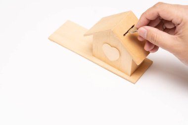 Property investment and house mortgage financial concept, Hand putting money coin stack with wooden house. selective focus. isolated on white background.