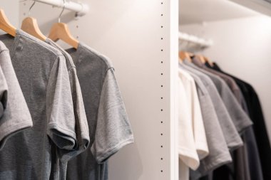 Gray clothes on clothing rack. gray t-shirt  wear on hangers in closet or spring cleaning concept. Summer home wardrobe. Clothing hanging on a clothing rack in a shop or home closet.