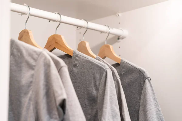 Gray clothes on clothing rack. gray t-shirt  wear on hangers in closet or spring cleaning concept. Summer home wardrobe. Clothing hanging on a clothing rack in a shop or home closet.