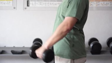 4K görüntüleri kapalı spor salonunda tanınmayan birini gösteriyor. Hammer Curl ağırlık egzersizi yapan bir adam. Spor salonunda vücut geliştirme halterleri. Spor salonunda eğitim..