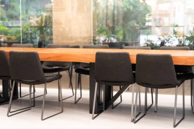 Masa ve sandalyeler toplantı odasında. Toplantı odası profesyonel kurul odası. Doğal ışıklı sandalyelerle aydınlatılmış ve masa boş kimse yok.. 