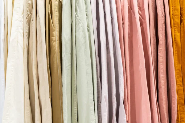 選択フォーカス ファッション 服のコンセプト 服やパンツ多くの色は デザイナーの服店で棚に掛けます 店内の衣料品棚に掛かる服 — ストック写真
