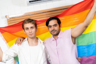 Evde Igbt gökkuşağı bayrağı tutan eşcinsel çift. Seçici odaklanma. Eşcinsel çift gökkuşağı bayrağıyla sarılıp sevgilerini gösteriyorlar. LGBT ve aşk konsepti. neşeli gurur ve gökkuşağı geçmişi.