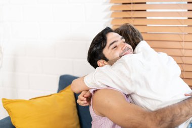 Eşcinsel Çift Evdeki Koltukta Birlikte Oturur. Erkek arkadaşlar birbirlerine sarılıp kucaklaşıyorlar. Eşcinsel bir çift birbirine sarılır..