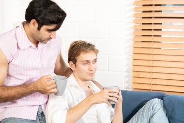 Lgbt gay çifti ellerinde kahve tutuyor. Evde kahve içen eşcinsel erkekler, gay gururu ve evlilik hayatı..