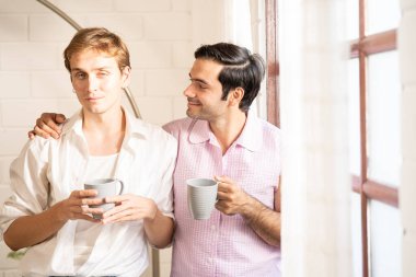 Lgbt gay çifti ellerinde kahve tutuyor. Evde kahve içen eşcinsel erkekler, gay gururu ve evlilik hayatı..