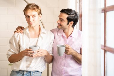 Lgbt gay çifti ellerinde kahve tutuyor. Evde kahve içen eşcinsel erkekler, gay gururu ve evlilik hayatı..