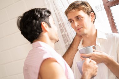 Lgbt gay çifti ellerinde kahve tutuyor. Evde kahve içen, eşcinsel gururu olan ve evlilik hayatı yaşayan iki eşcinsel. LGBT aşk konsepti.