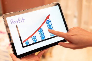 Using tablet to see business growth predication graph with blur background of department store. Business successful concept. Concept of growth planning and strategy. clipart
