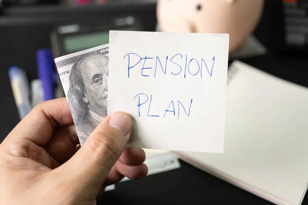 Paper note with text PENSION PLAN with stationery and dollar on desk. Pension Plan. Retirement concept. Pension calculation concept.