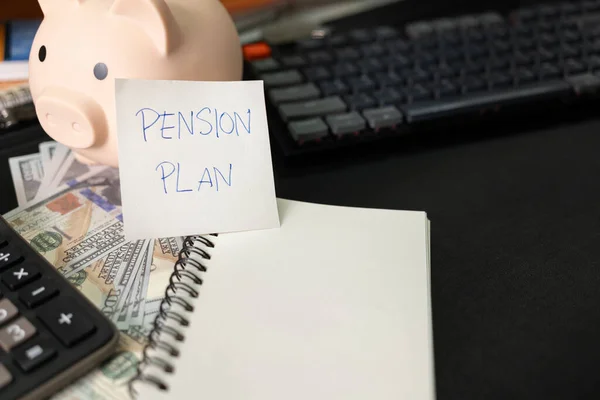 Paper note with text PENSION PLAN with stationery on desk. Pension Plan. Retirement concept. Pension calculation concept. copy space for text. Piggy bank.