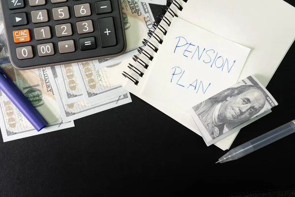 Paper note with text PENSION PLAN with stationery and dollar on desk. Pension Plan. Retirement concept. Pension calculation concept.