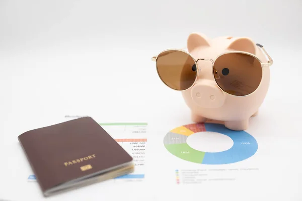 Budget management for vacation concept. Passport, piggy bank wearing Sunglasses for vacation trip and budget graph. Preparing for vacation.
