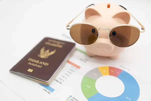 Budget management for vacation concept. Passport, piggy bank wearing Sunglasses for vacation trip and budget graph. Preparing for vacation.