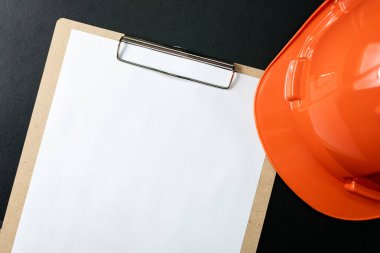 Siyah arkaplanda boş pano kağıdı ve başlık veya güvenlik kaskı izole edilmiş..