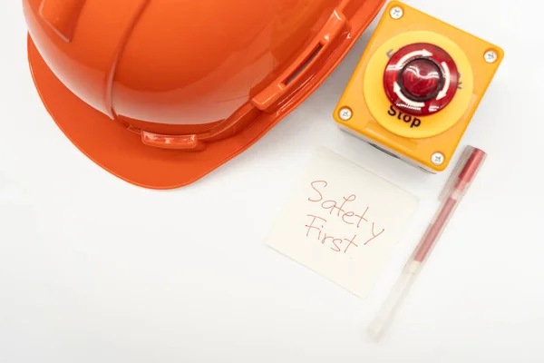 オレンジの安全帽子 メッセージの安全第一 赤いペンおよび緊急停止ボタンは白い背景で隔離しました 安全第一概念 テキストのコピースペース — ストック写真