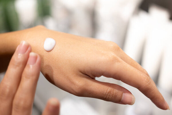 Woman testing and applying moisturizer lotion in her hand. product testing, care cosmetics. Healthy skin care.