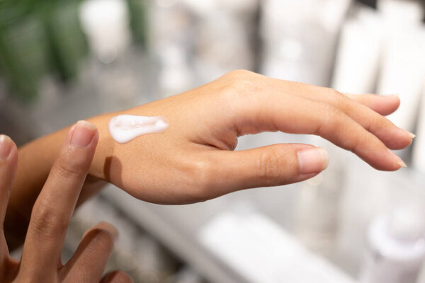 Woman testing and applying moisturizer lotion in her hand. product testing, care cosmetics. Healthy skin care.