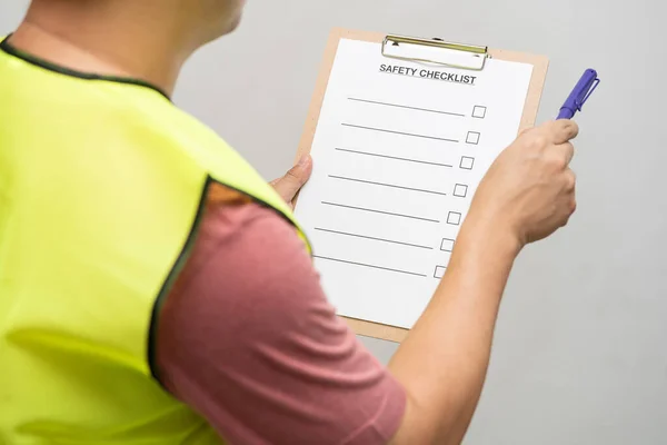 Action of safety officer is writing and check on checklist document during safety audit and inspection. safety checklist sheet to verify working condition.