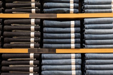 Perakende mağazasının giysilerinde kot pantolonlu rafları göster.