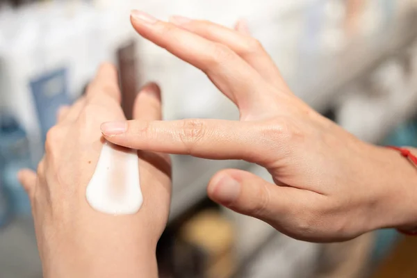 Woman testing and applying moisturizer lotion in her hand. product testing, care cosmetics. Healthy skin care.