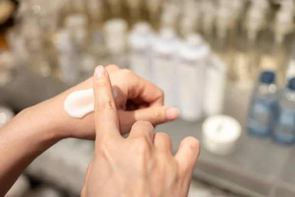 Woman testing and applying moisturizer lotion in her hand. product testing, care cosmetics. Healthy skin care.
