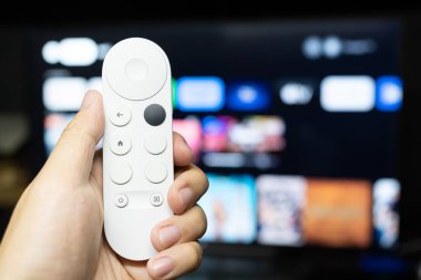 Televizyon izlemek için modern kumandayı tutuyorum..