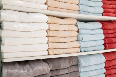 Çok renkli banyo havlusu yığını. Süpermarketteki raflarda duran havlular var. Aile alışverişi.