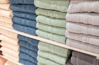 Çok renkli banyo havlusu yığını. Süpermarketteki raflarda duran havlular var. Aile alışverişi.