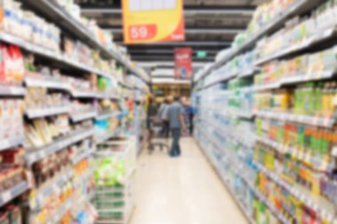 Arka plan için alışveriş merkezinin iç kısımlarında renkli raflar bulunan soyut bulanık süpermarket koridoru, bulanık arkaplan ve arka plan olarak tanınmayan müşteriler.