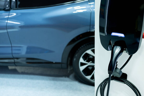 Электрический автомобиль небольшое домашнее зарядное устройство с кабелем. Заглушка для автомобиля с электрическим двигателем. Зарядное устройство. Чистая энергия. Точка зарядки на парковке. Технологии будущего.