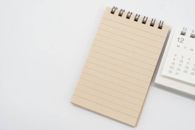 Kahverengi çizgili kağıtları olan boş bir Spiral not defteri ve izole arkaplanda DECEMBER için basit masa takvimi. Kopyalama alanı ile bellek kavramı.