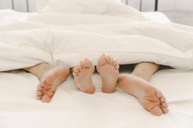 Yatakta sevişen bir çiftin arka görüntüsü. Tutkulu bir aşk. Balayında yatakta yatan genç bir çiftin ayakları. Birbirine aşık bir çift. Kavram: aşk, seks, tatlım, tatlı, aktivite, yaşam tarzı.