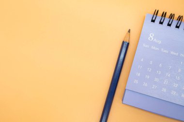 Ağustos takvimi ve kalem turuncu arka planda izole edilmiş, iş ya da seyahat planlama konsepti için planlama. Metin için alanı kopyala.