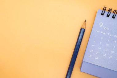 Eylül takvimi ve kalem turuncu arka planda izole edilmiş, iş ya da seyahat planlama konsepti planlanıyor. Metin için alanı kopyala.