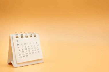 Turuncu arka planda izole edilmiş bir yılı olmayan Temmuz ayı için masa takvimi. Takvim konsepti kopyalama alanı. Planlayıcı ve Yönetim için Masaüstü Takvimi.