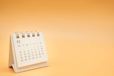 Turuncu arka planda izole edilmiş bir yılı olmayan Kasım için masa takvimi. Takvim konsepti kopyalama alanı. Planlayıcı ve Yönetim için Masaüstü Takvimi.