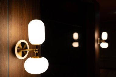 Lambanın içinde lamba var. Duvarda parlıyor. Arka planda fotokopi odası var..