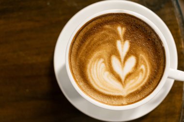 Sıcak kahve kapuçino latte sanatı ahşap masada..