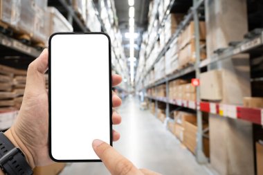 Bulanık mobilya deposundaki boş cep telefonu. Boş bir akıllı telefonu tutan eli olan bir depo. İnternetten alışveriş, telefonla ödeme, sipariş ürün. Lojistik, iş, teslimat.