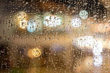 Bardağa Bokeh 'le birlikte yağmur damlaları damlıyor. Arkaplan olarak yağmur damlaları olan pencere camı.