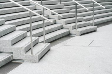 Geniş, pürüzsüz beton merdivenleri ve pürüzsüz çelik korkulukları olan modern bir merdiven. Basamaklar simetrik bir şekilde iniyor, temiz ve minimalist bir estetik yaratıyor.. 