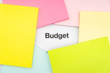 Renkli yapışkan notlu bütçe metni. Bir yığın boş yapışkan kağıdın arkaplanı metin bütçesi ile değil.