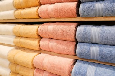 Çok renkli banyo havlusu yığını. Süpermarketteki raflarda duran havlular var. Aile alışverişi.