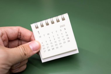 Ocak 2025 arkaplanı için el ele tutuşan mini takvim. 2025 JAN takvimi ile takvim kavramı.