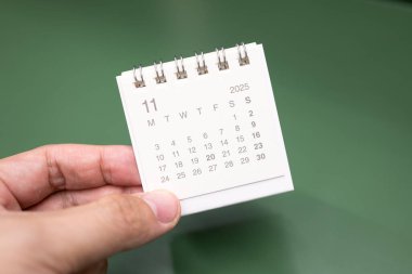 Kasım 2025 arkaplanı için el ele tutuşan mini takvim. Takvim kavramı 2025 NOV takvimi. Yeşil arkaplanda takvim.