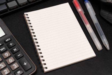 Hesap makinesi ve ofis malzemeleriyle dolu boş bir defter. Uzayı metin için kopyala. Bir yazıt, iş konsepti için yer.