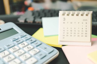 Mart 2025 'in masa takvimi ve yapışkan bir not. Takvim kavramı 2025 MAR takvimi. 2025 mali durumu için hesap makinesi ve hava durumu. Para, Bütçe, vergi, yatırım ve mali.