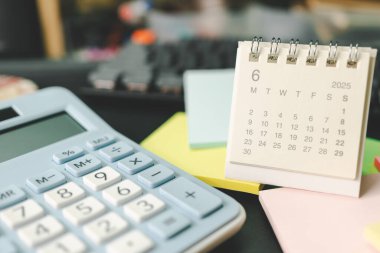 Haziran 2025 için yapışkan notlu masa takvimi. 2025 Haziran takvimi takvim kavramı. 2025 mali durumu için hesap makinesi ve hava durumu. Para, Bütçe, vergi, yatırım ve mali.